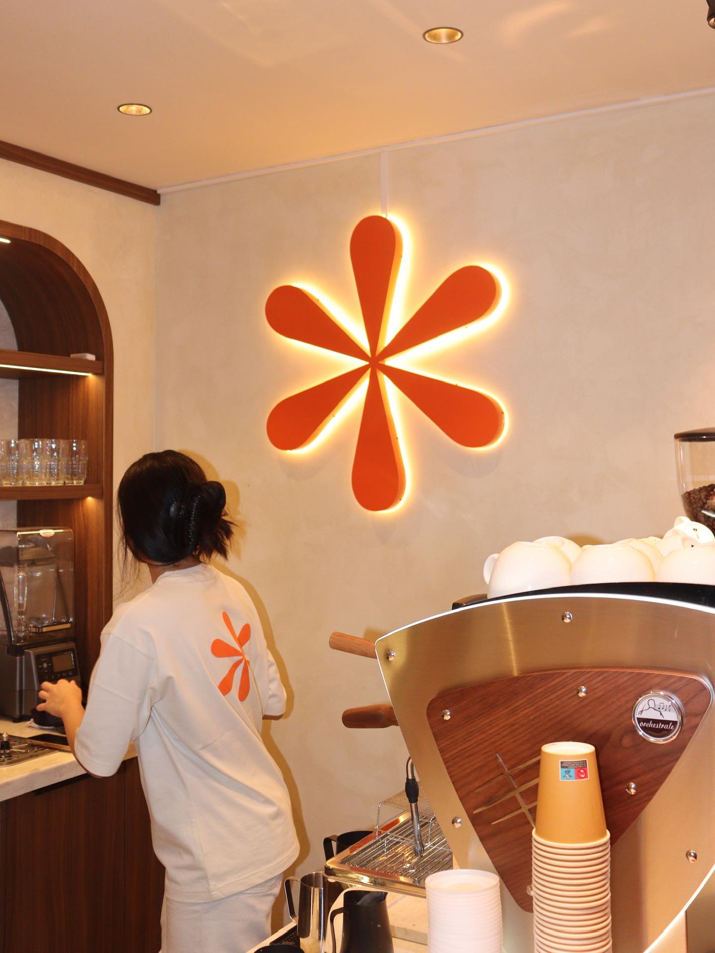 Het interieur van Mana Café: de oranje bloem aan de muur en de espressomachine